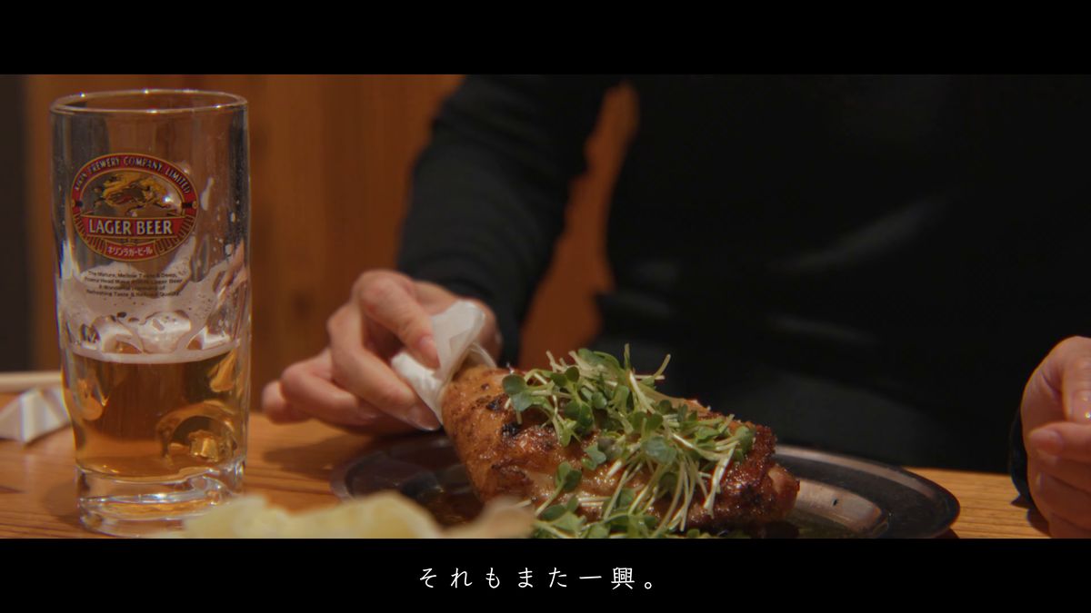 紙ナプキンで骨付鳥を持つ手元とビール