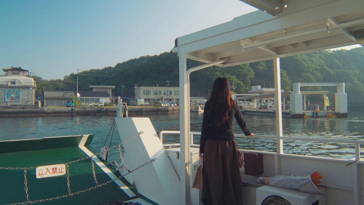 船の甲板に立って港を見送る後ろ姿
