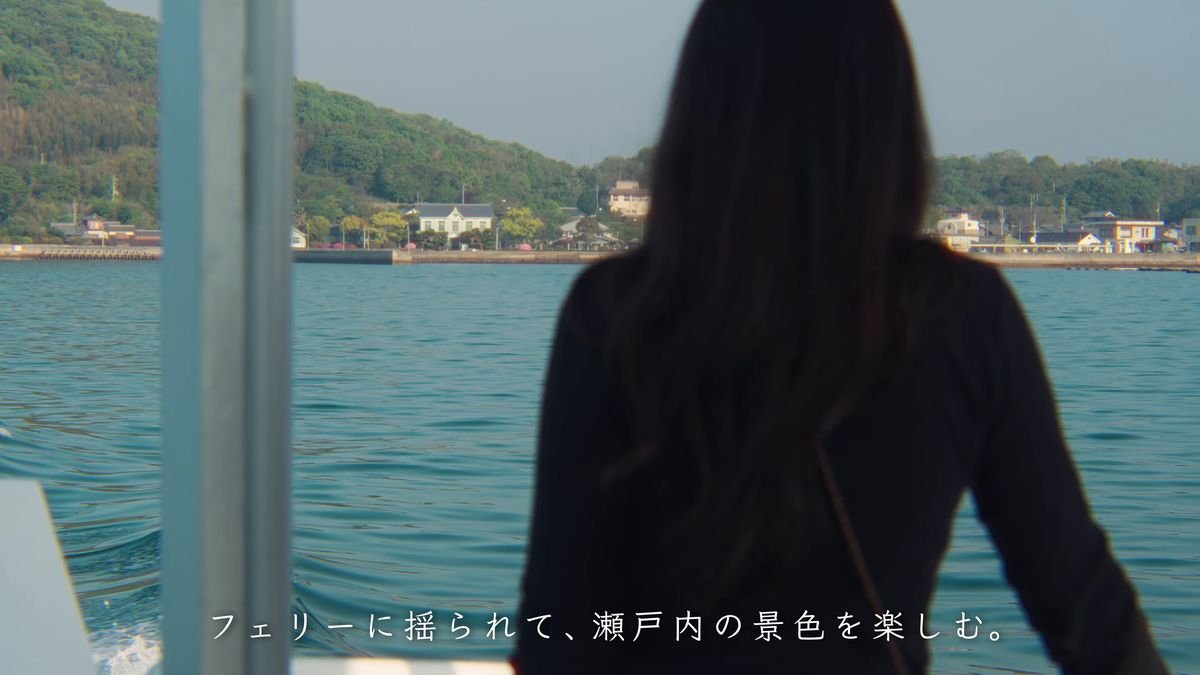 船上から島影を眺める後ろ姿