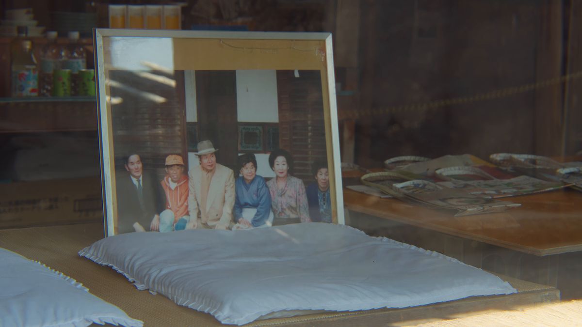 布団の上に立てかけた額入りの古い記念写真