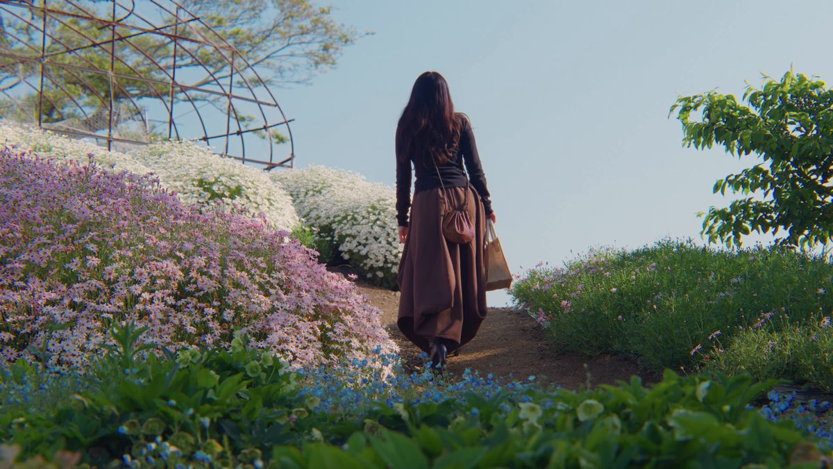 芝桜と白い花の間の道を上る後ろ姿