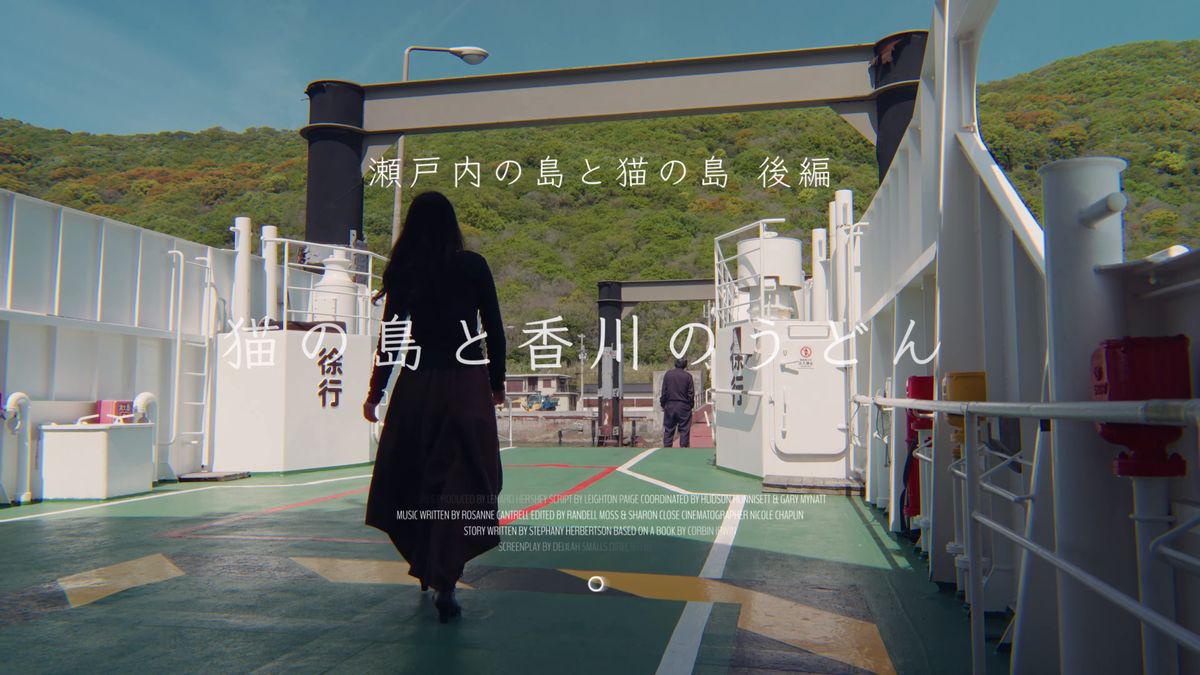 フェリーのデッキに立つ後ろ姿と緑の島