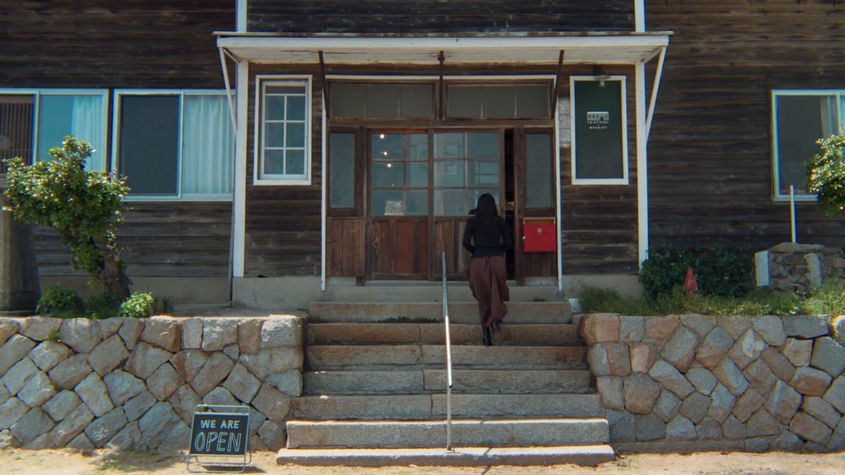 石段の上の木造校舎の玄関と「WE ARE OPEN」の札
