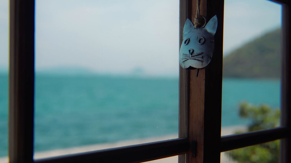 窓辺に下がる猫の形の飾りと、青い海