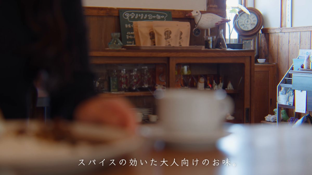 カウンターの棚と、ぼけた後ろ姿越しのテーブル