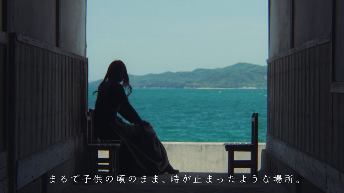 廊下の先の海を眺めて座る後ろ姿