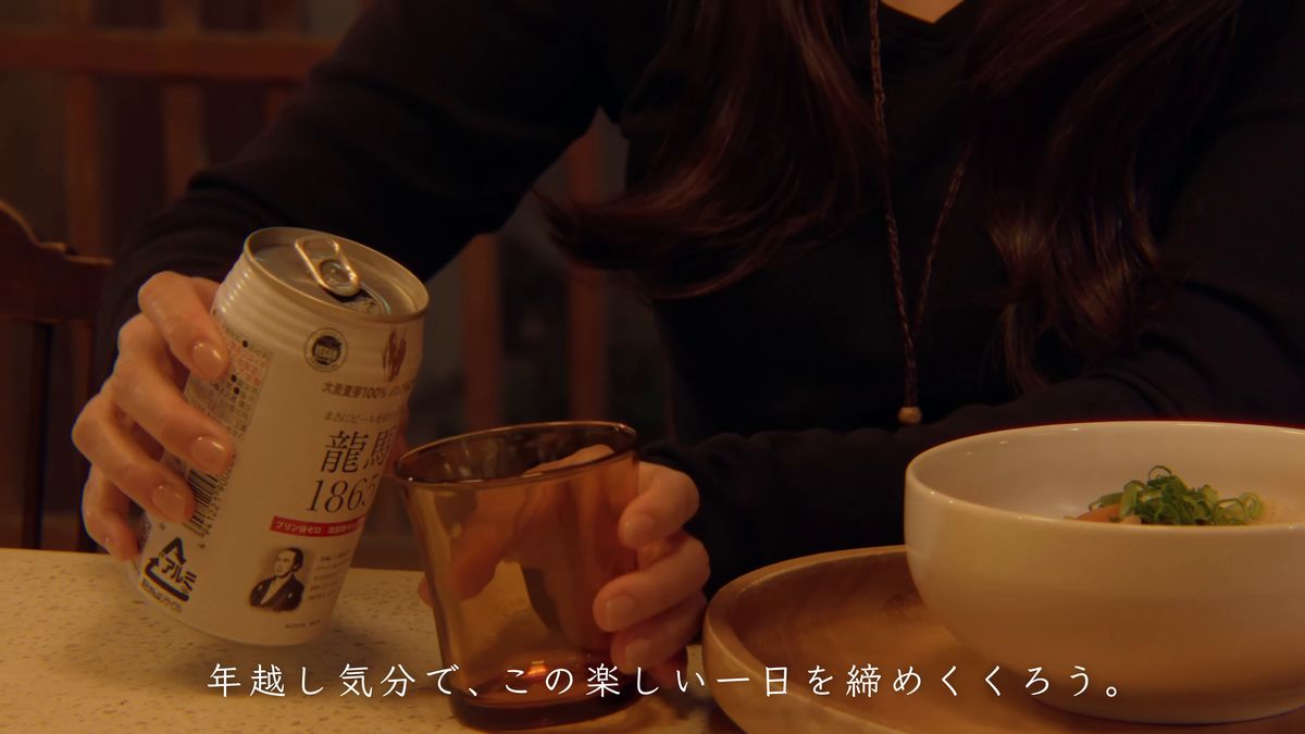 缶の飲み物をグラスに注ぐ手元と、うどんの丼