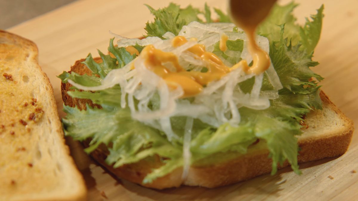 葉野菜と玉ねぎの千切りにソースをかける