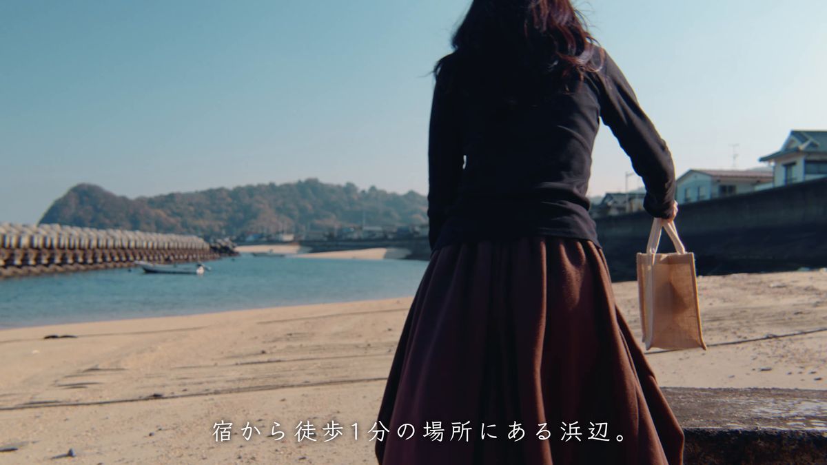 トートバッグを提げて浜辺を歩く後ろ姿