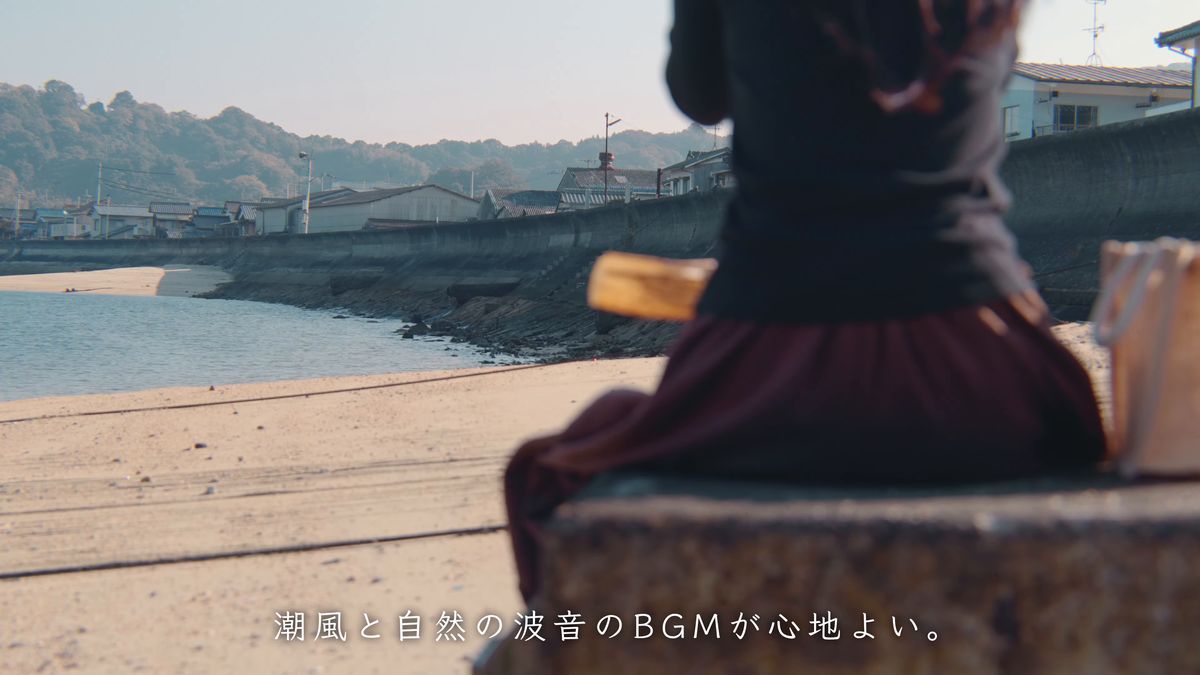 石段に腰かけて浜を眺める後ろ姿