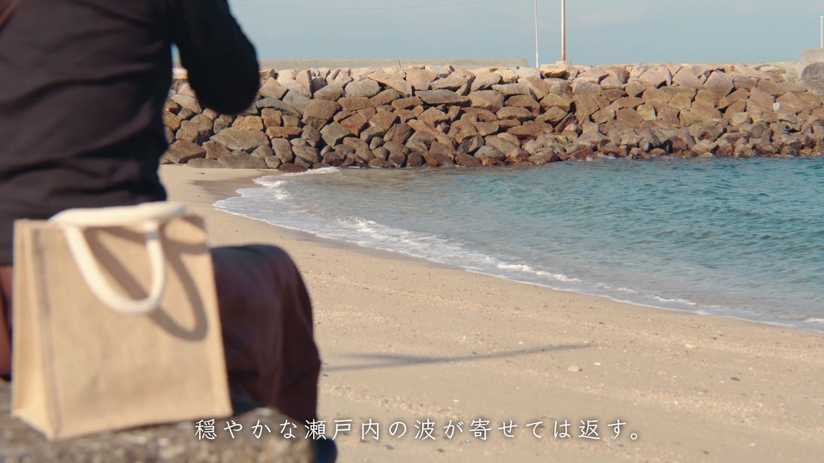 石積みの堤のそばに置いたトートバッグと波打ち際
