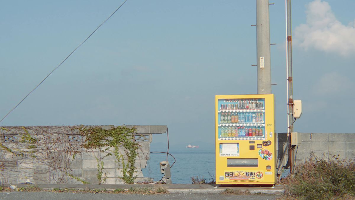 海辺のブロック塀の前の黄色い自動販売機