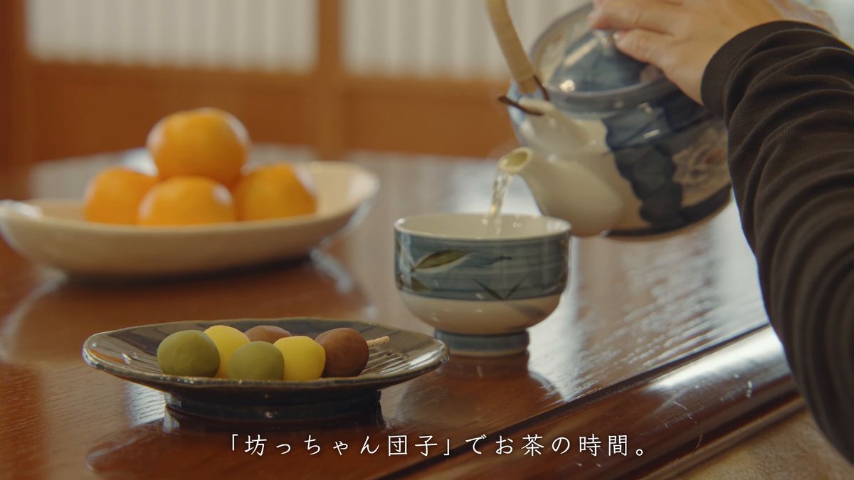 みかんと団子の皿を前に急須からお茶を注ぐ
