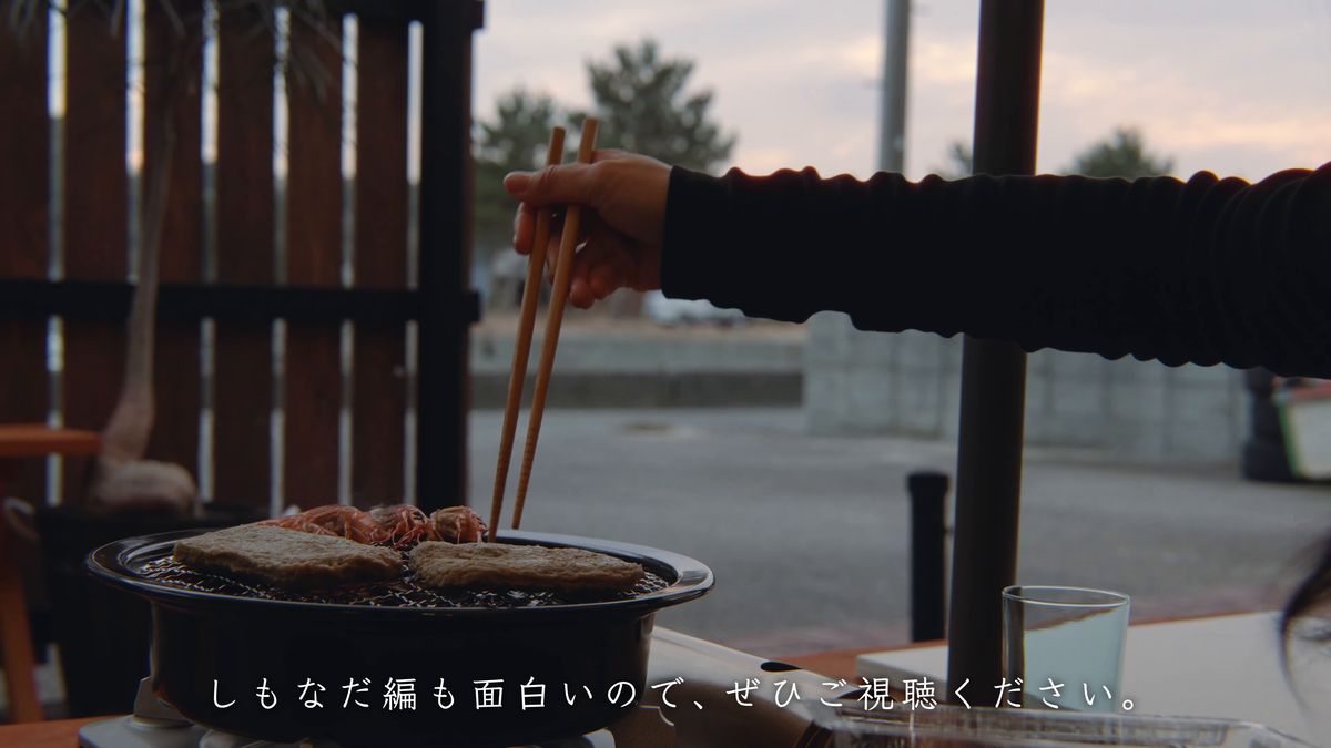 窓辺の七輪に箸を伸ばす手元