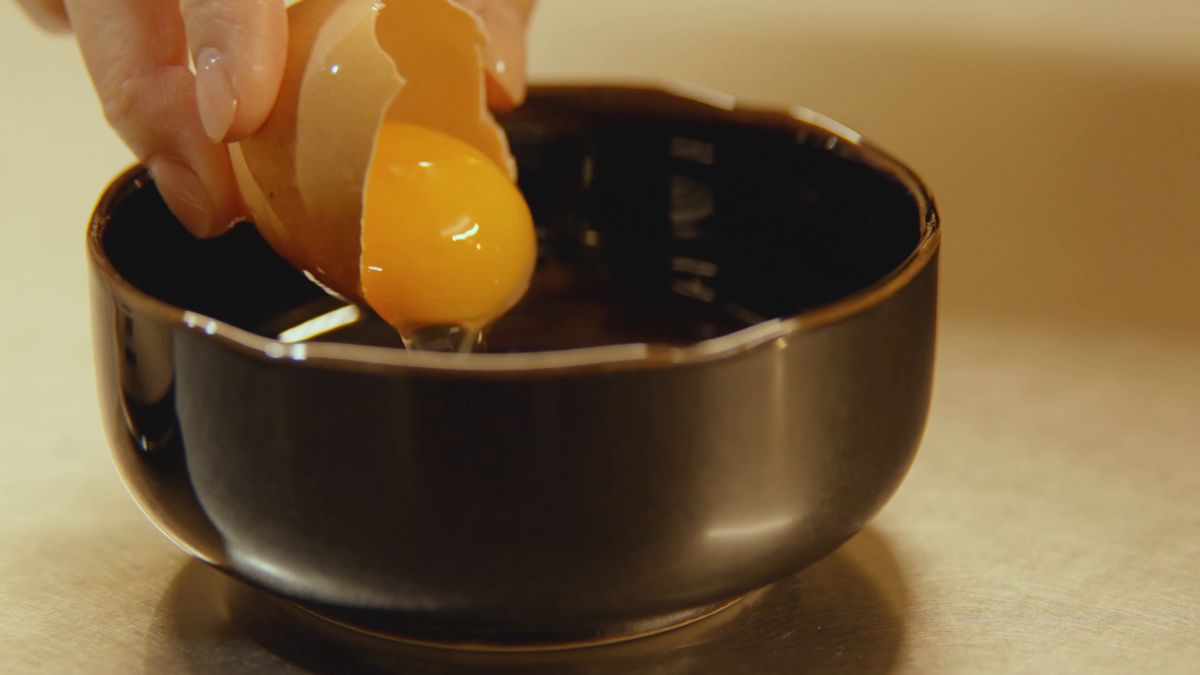 黒い器のタレに卵黄を落とす