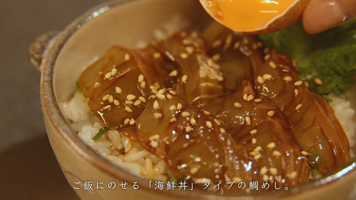 ごまを散らした刺身の上に卵黄を落とす