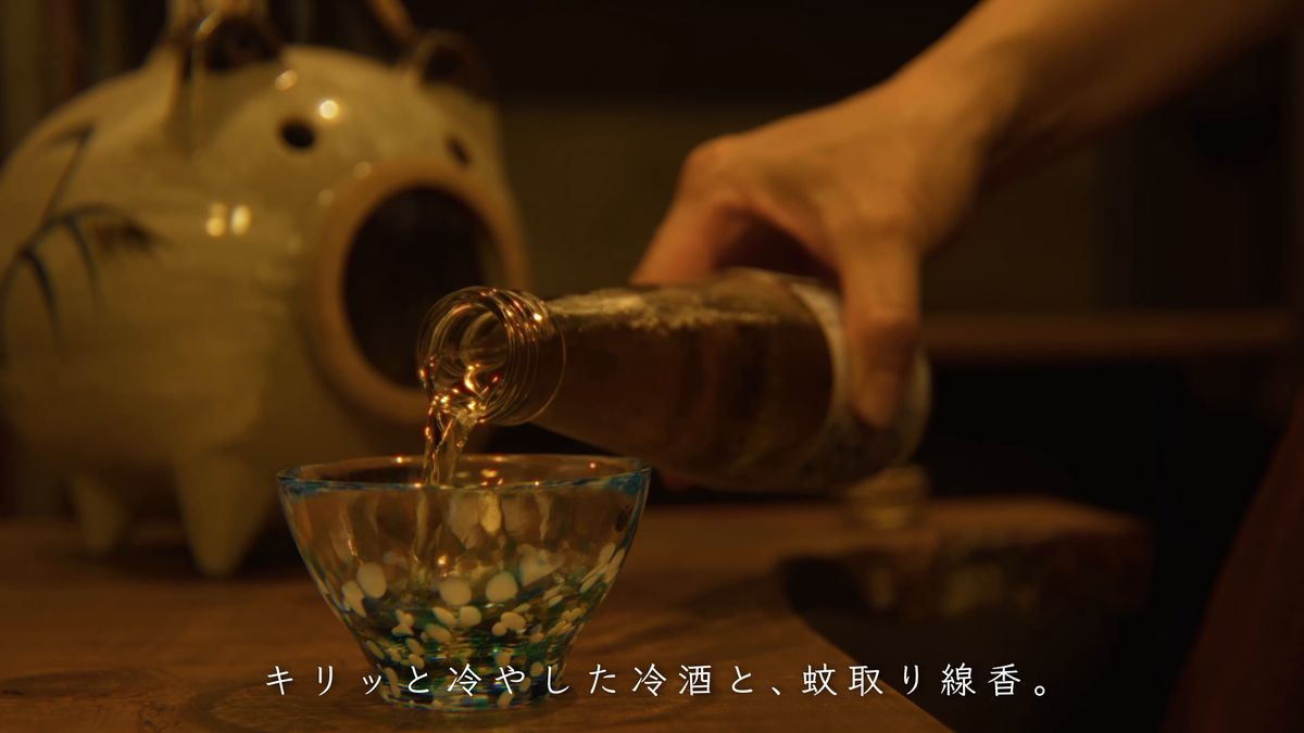 瓶からグラスに注ぐ手元と、蚊遣り豚