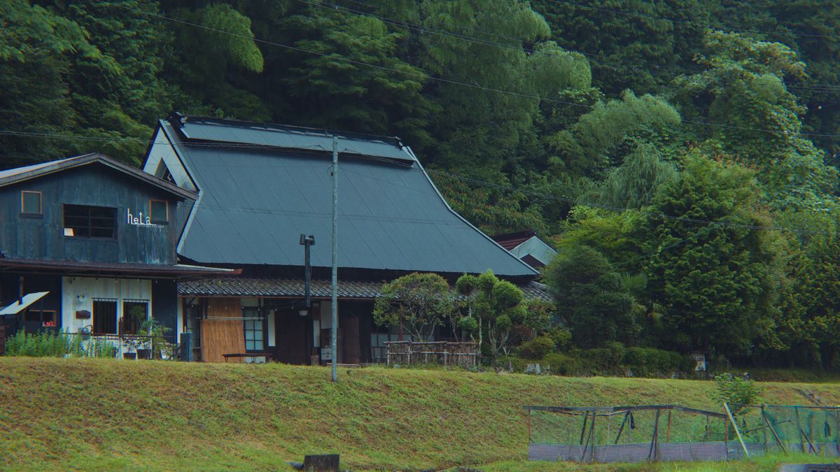 裏山の緑を背にした黒い屋根の古民家