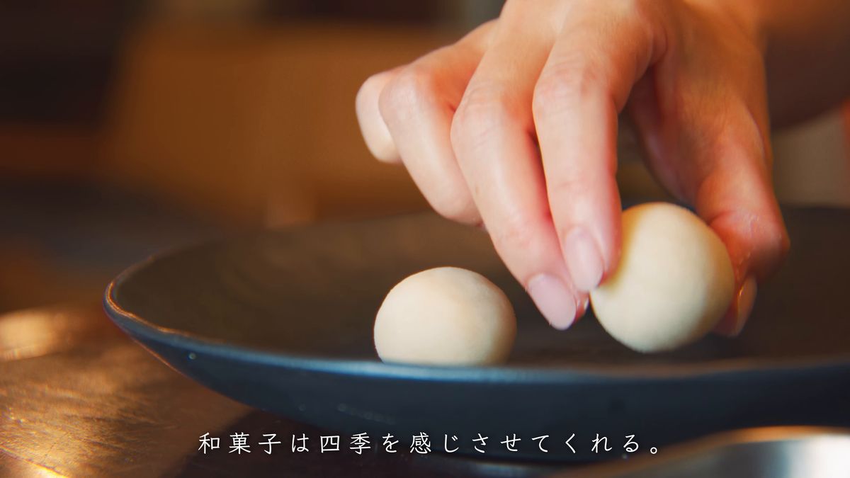 丸めた白あんを黒い皿に置く手元