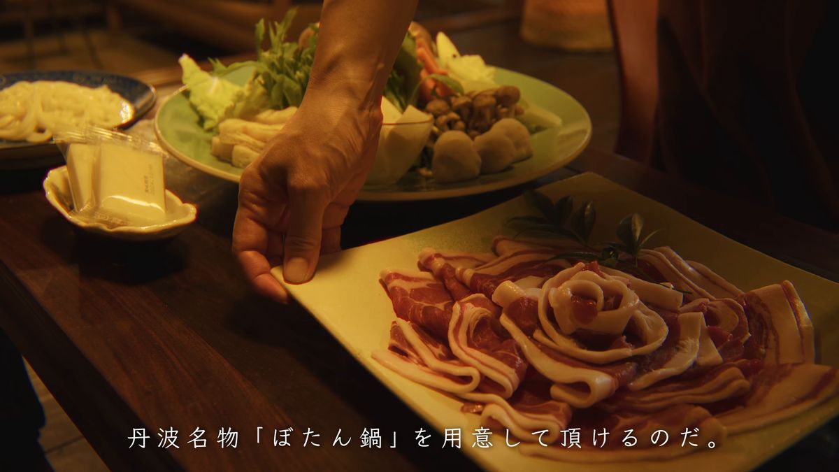 イノシシ肉の皿を卓に置く手元