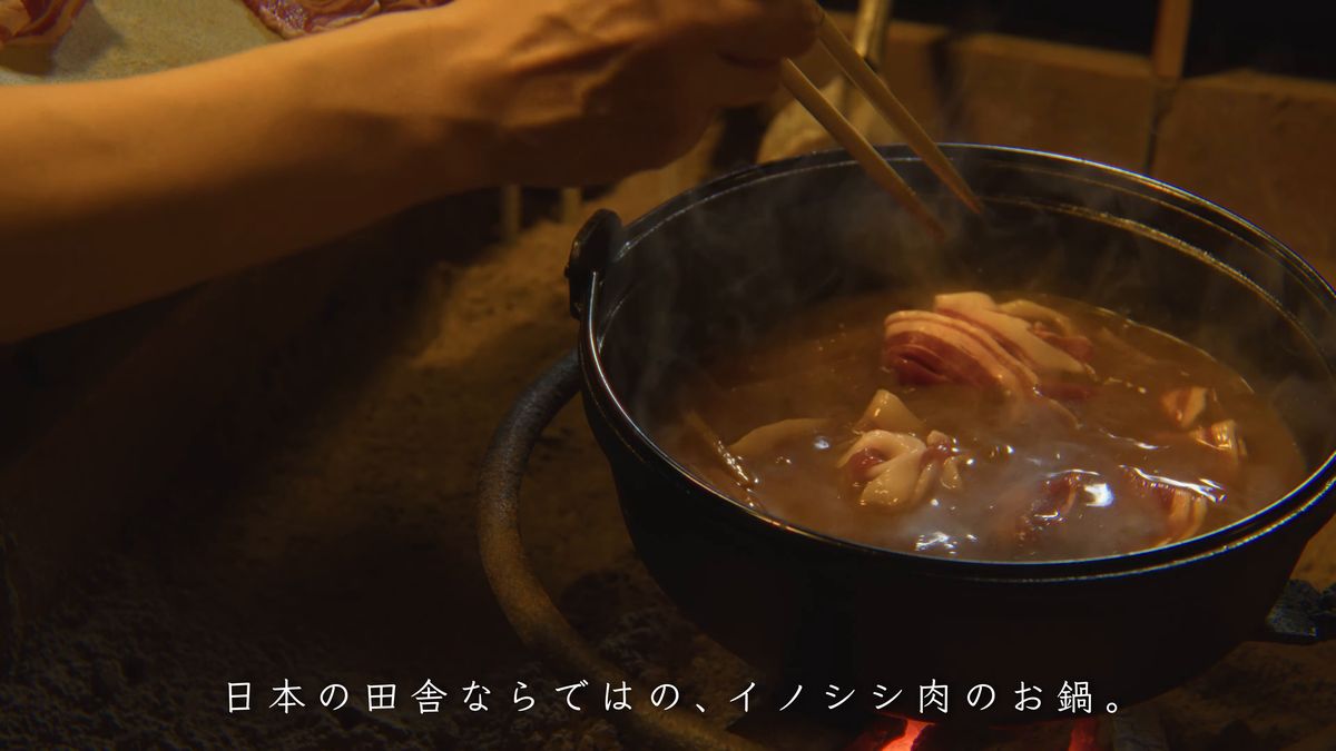 湯気の立つ鍋に肉を入れる