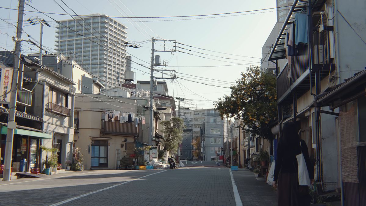 朝の光が差す下町の通りと、向こうの高層マンション