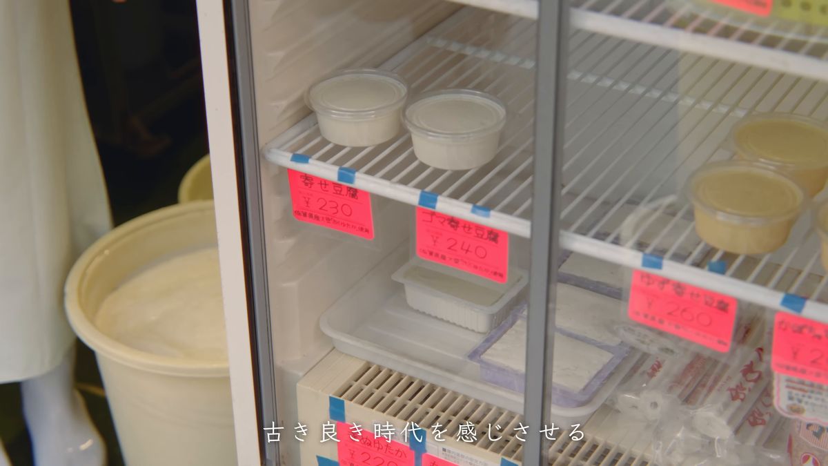 冷蔵ケースに並ぶ豆腐のパックと赤い値札