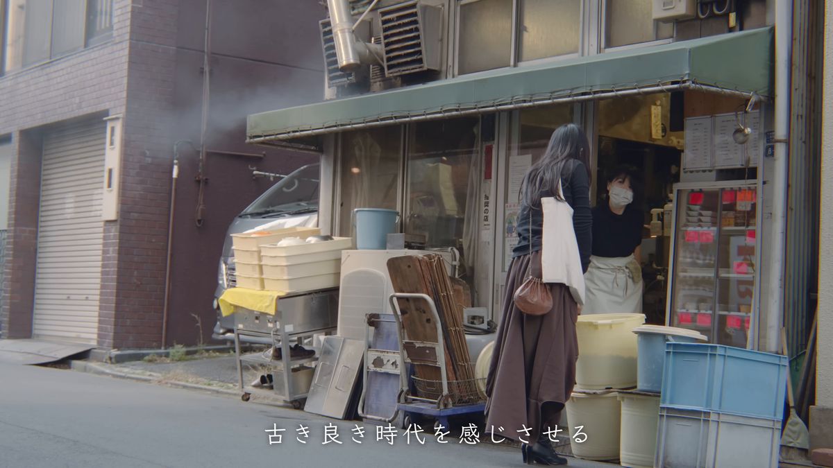 豆腐店の店先で買い物をする後ろ姿