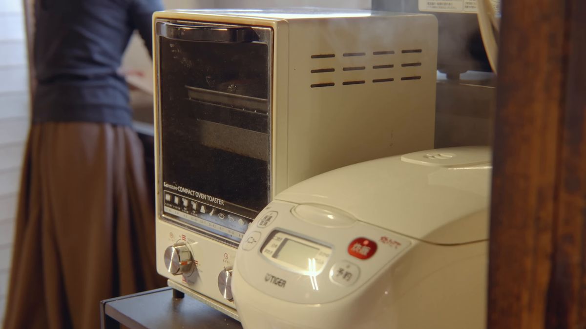 台所のオーブントースターと炊飯器の前に立つ後ろ姿