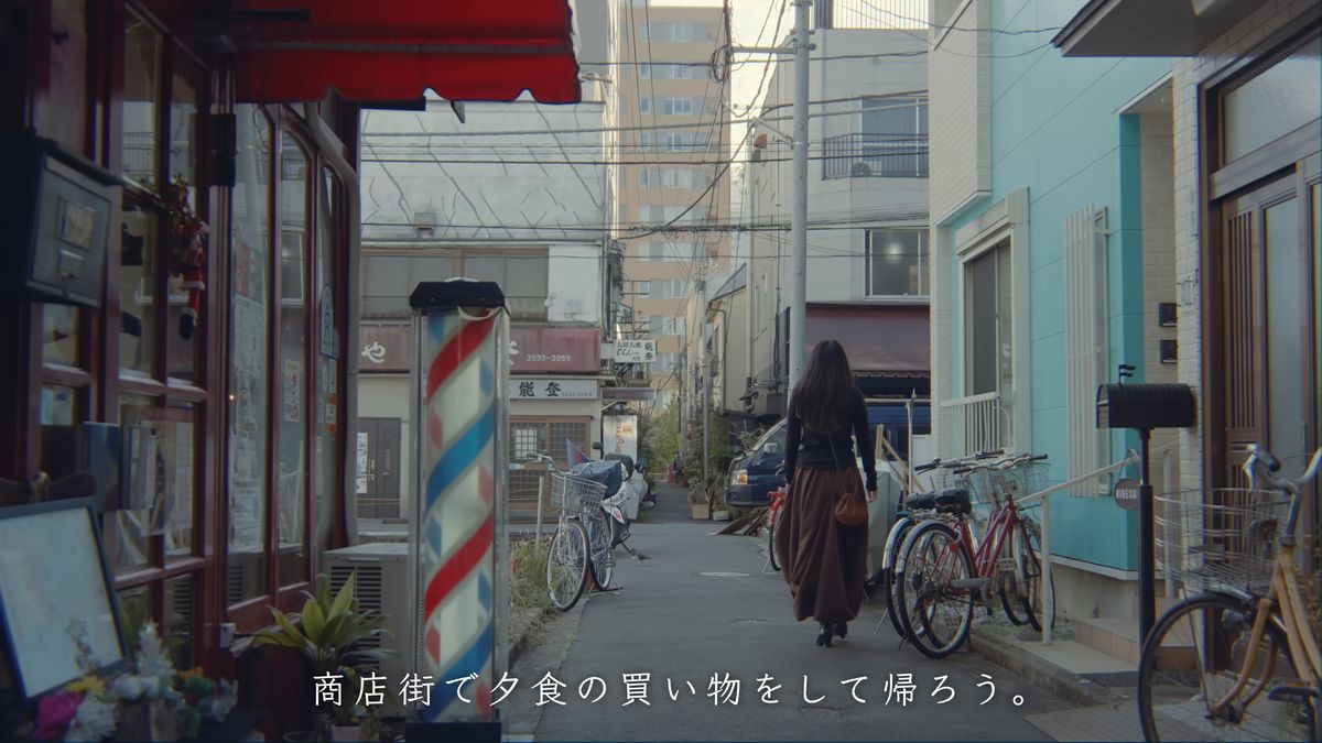 床屋のサインポールのある路地を歩く後ろ姿
