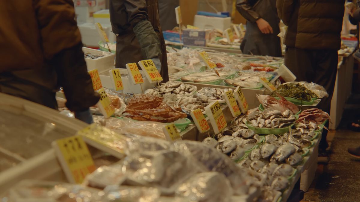 氷の上に魚介を並べた店先と買い物客