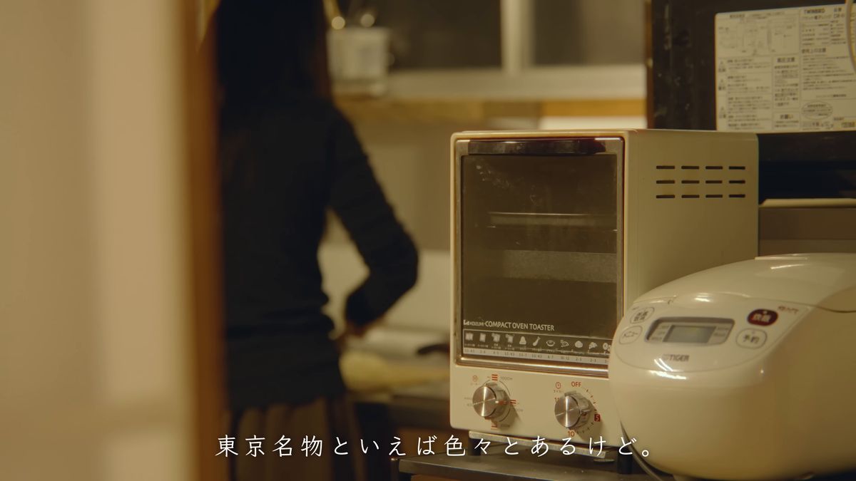 オーブントースターと炊飯器の並ぶ台所に立つ後ろ姿