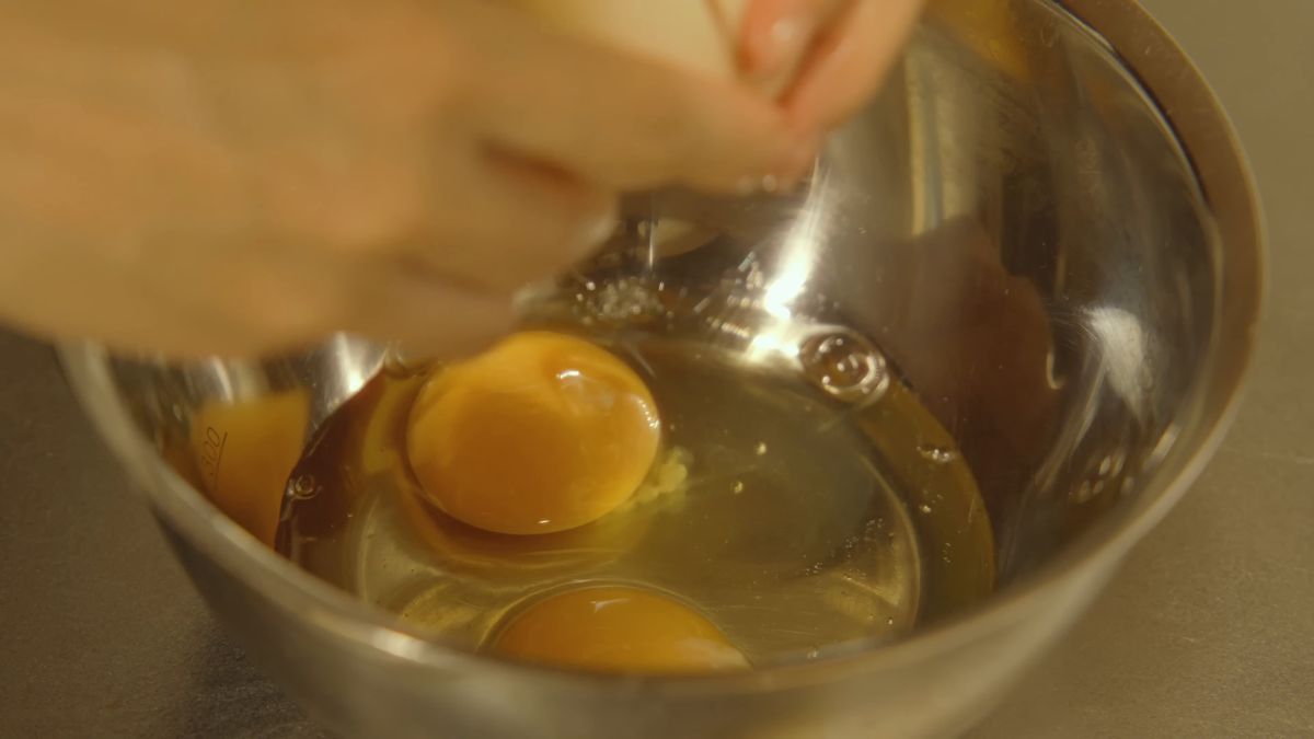 ボウルに卵を割る手元